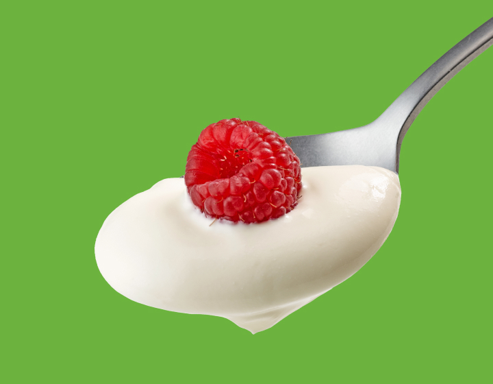 Spoon filled with yoghurt and a raspberry on top